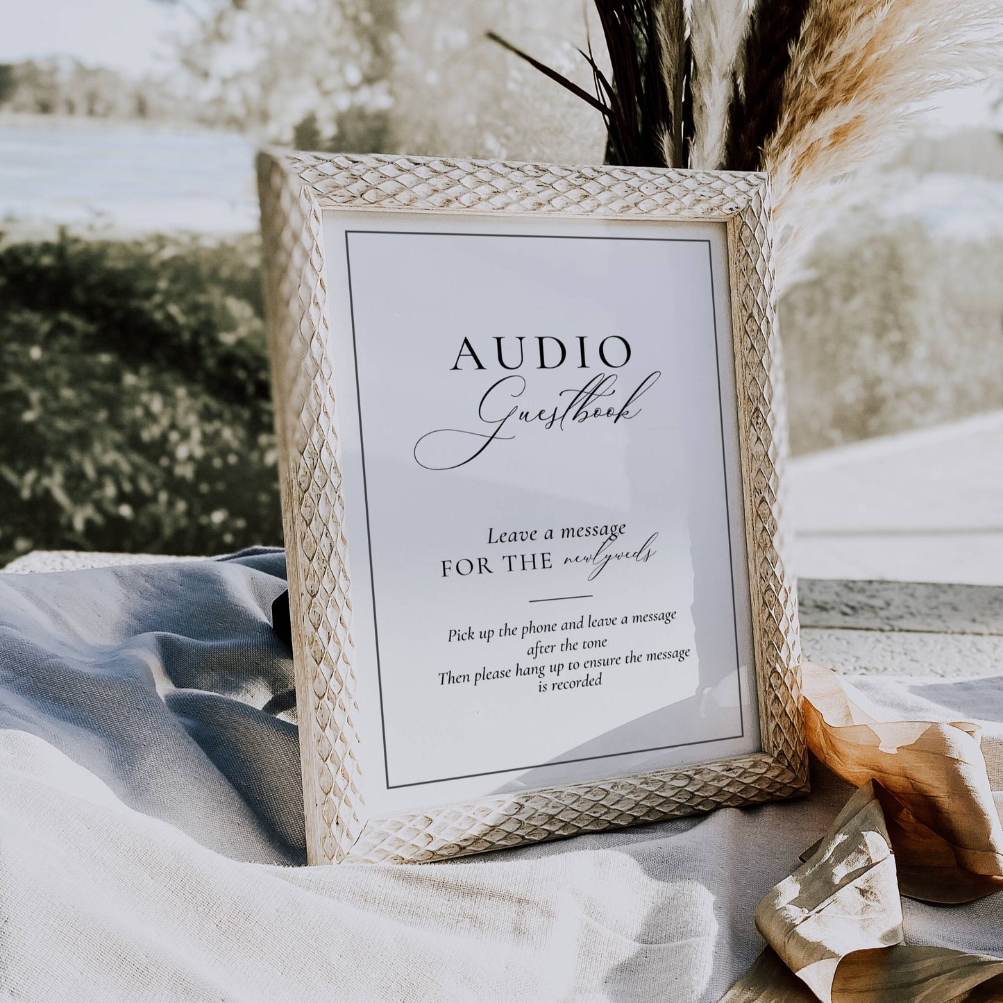 Wicker frame with 'Audio Guestbook' sign on a table outdoors