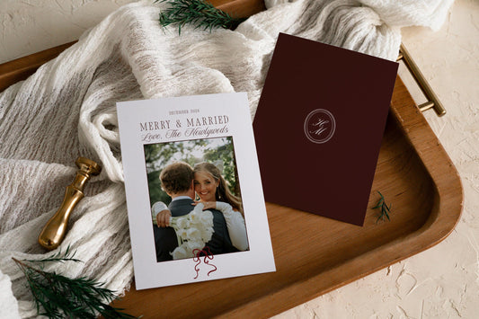 Merry and Married newlywed Christmas card template shown front and back on a wooden tray, with a wedding photo and a burgundy monogram back