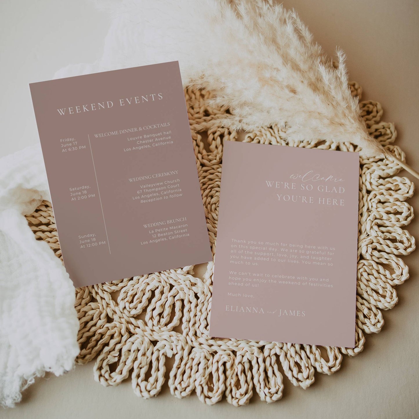 Two pink event invitations on a textured surface with pampas grass