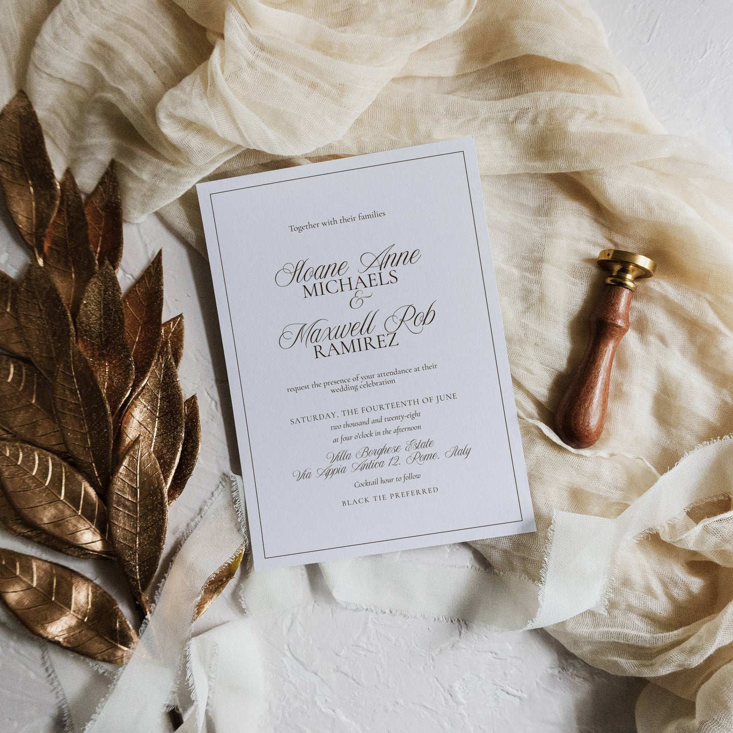 Wedding invitation card with gold leaf and pen on a textured surface