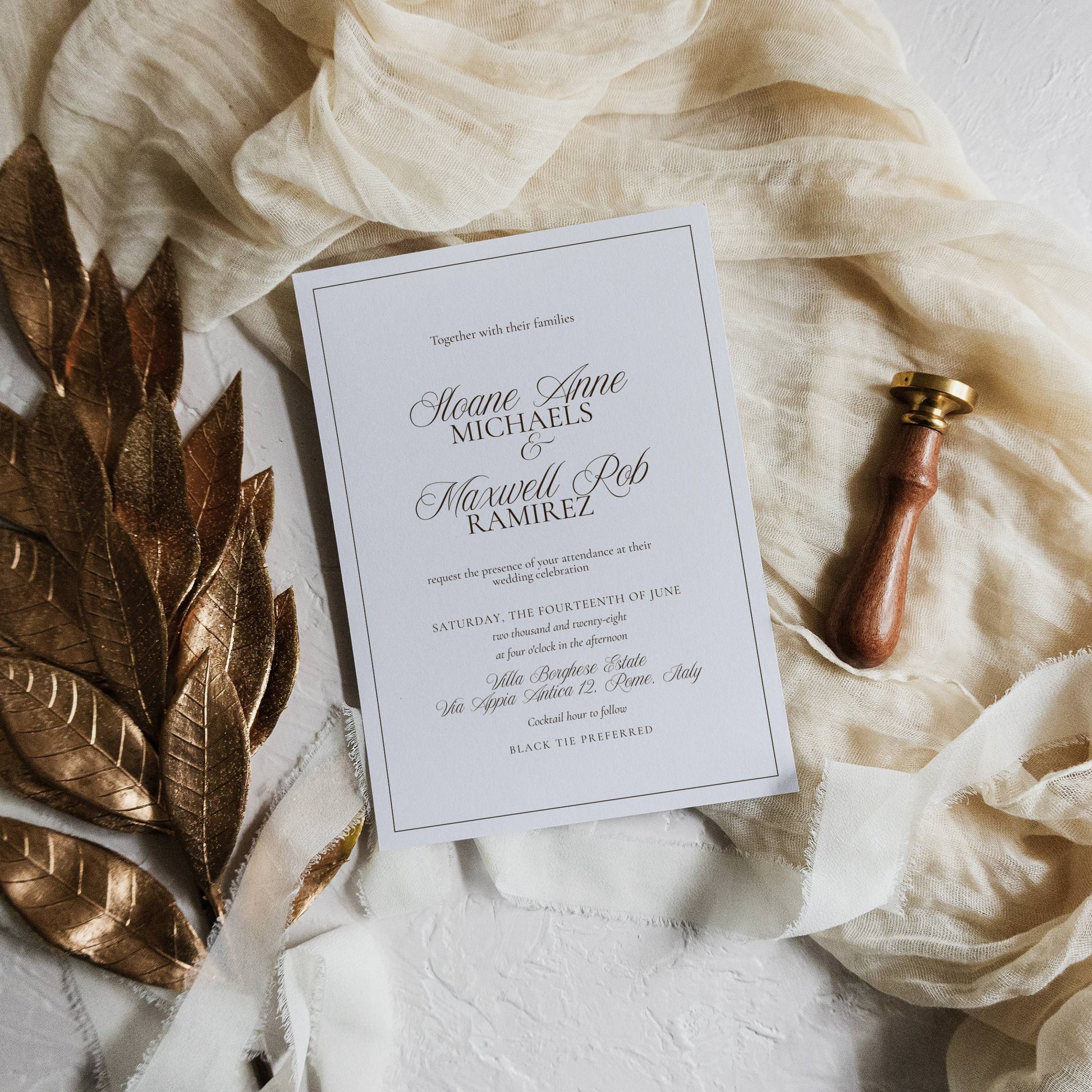 Wedding invitation card with gold leaf and pen on a textured surface