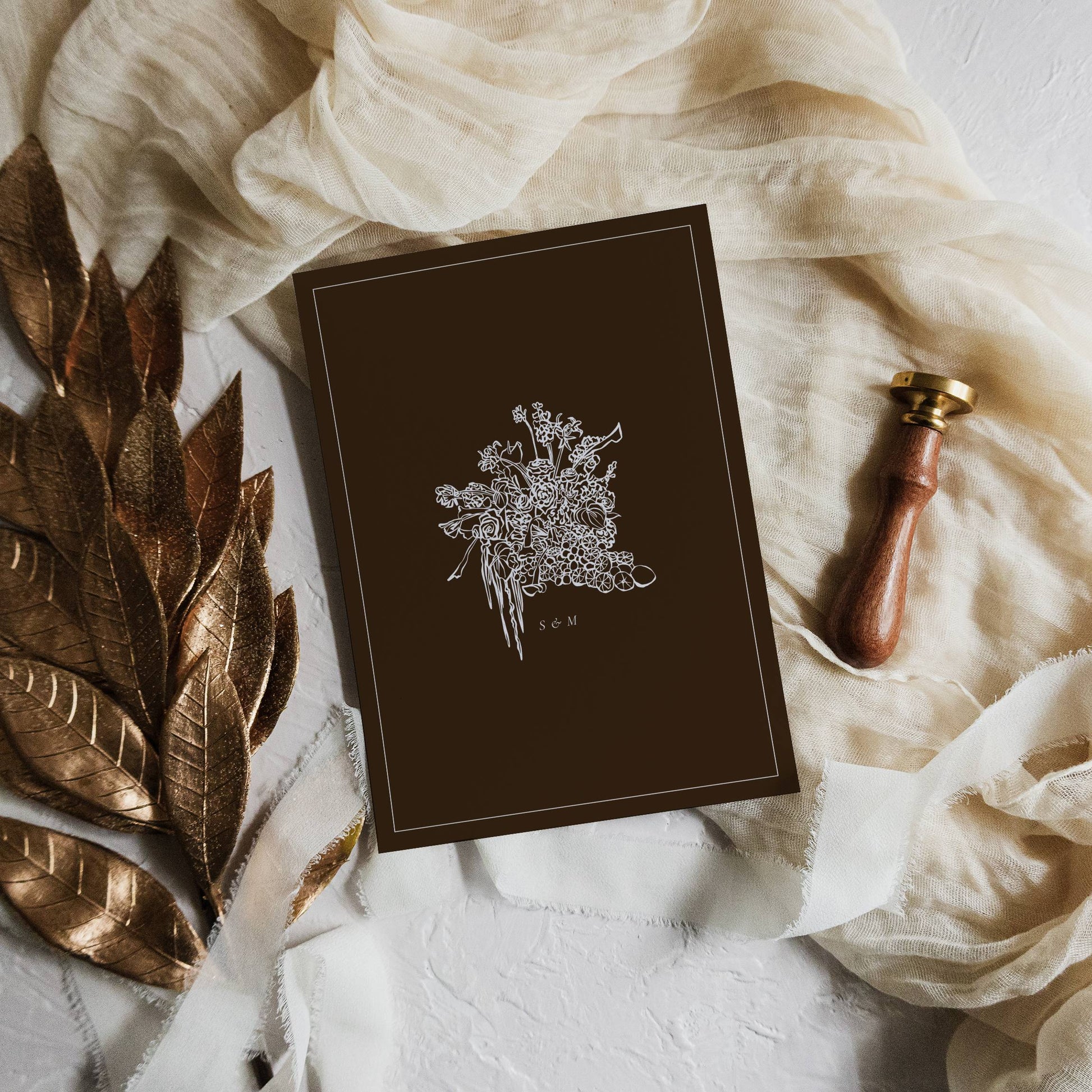 Decorative box with floral design, gold leaf, and pen on a textured surface