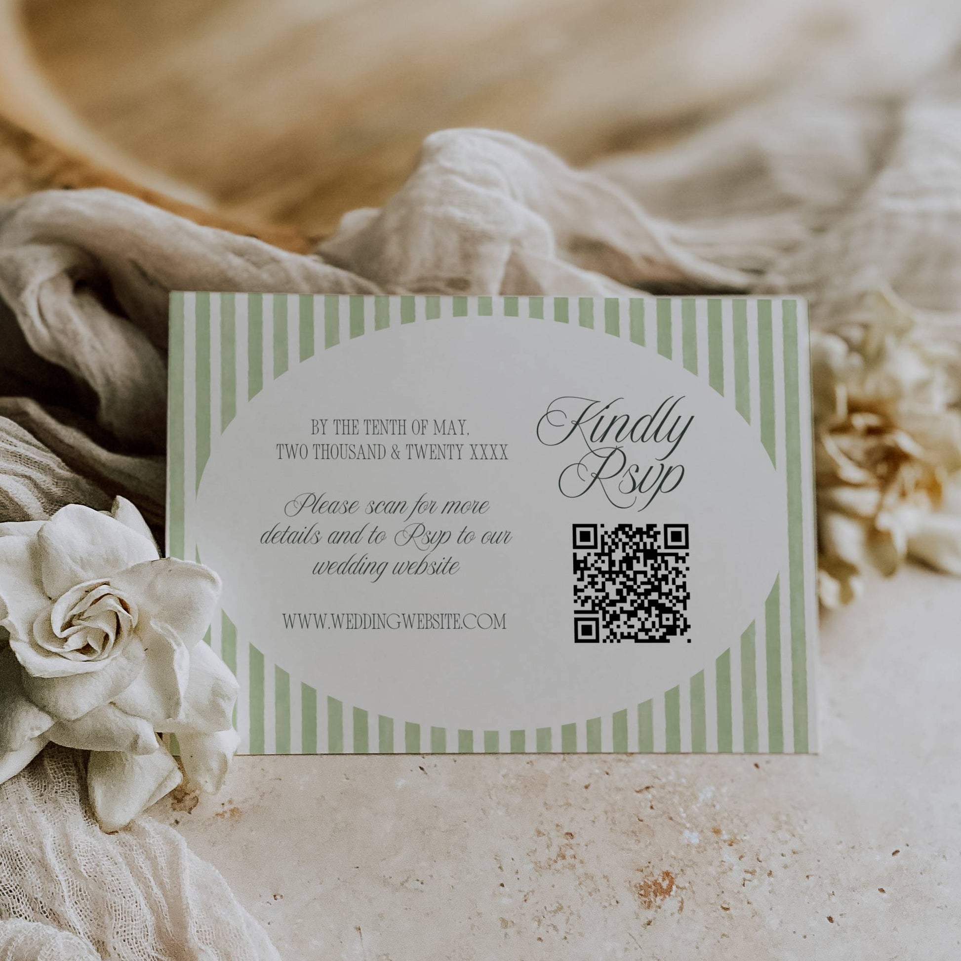 Wedding invitation card with QR code on a textured surface with flowers and fabric.