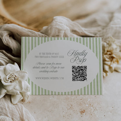 Wedding invitation card with QR code on a textured surface with flowers and fabric.