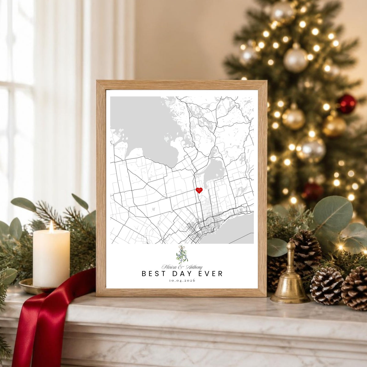Mistletoe holiday wedding map print in an oak frame on a Christmas mantel beside a lit tree, red ribbon and pinecones