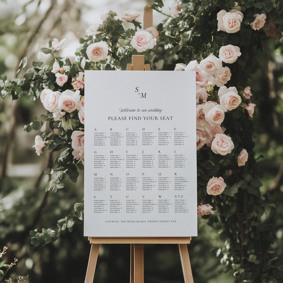 Alphabetical wedding seating chart displayed on a wood easel with blush garden roses and greenery