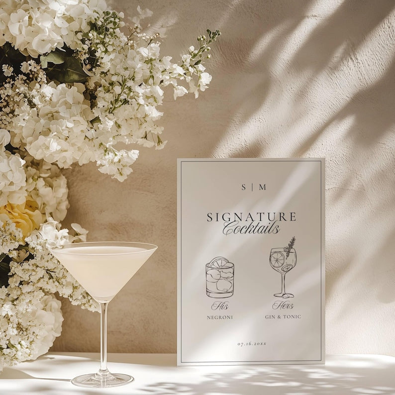 Signature cocktails sign beside a pale yellow cocktail with white florals and foliage