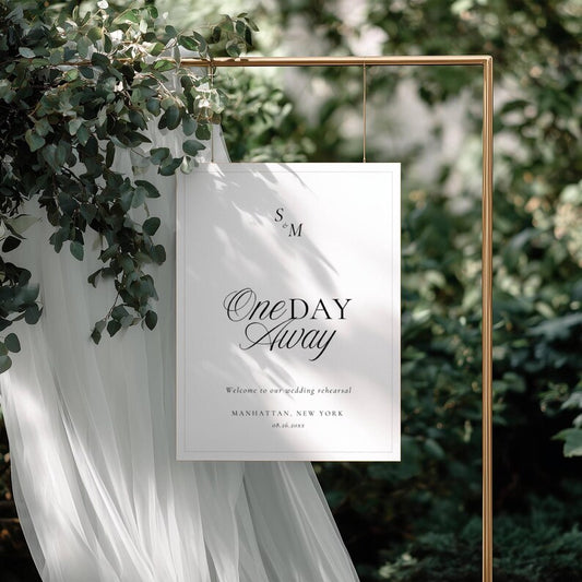 Black and white Old Money rehearsal welcome sign hanging from a gold metal frame with monogram and script