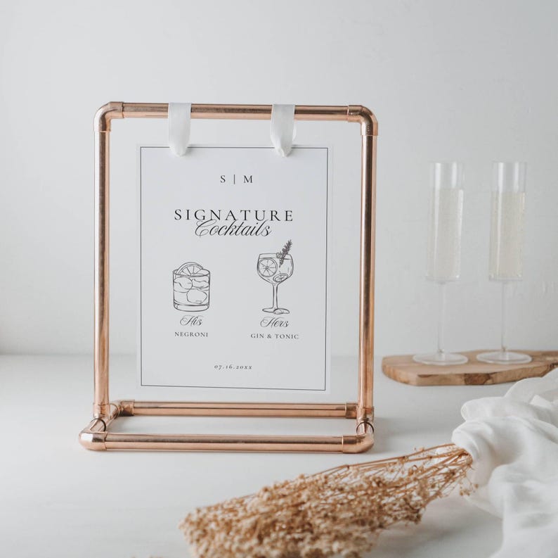 Signature drinks sign displayed in a copper metal frame with champagne flutes