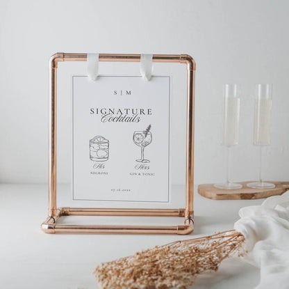 Signature drinks sign displayed in a copper metal frame with champagne flutes