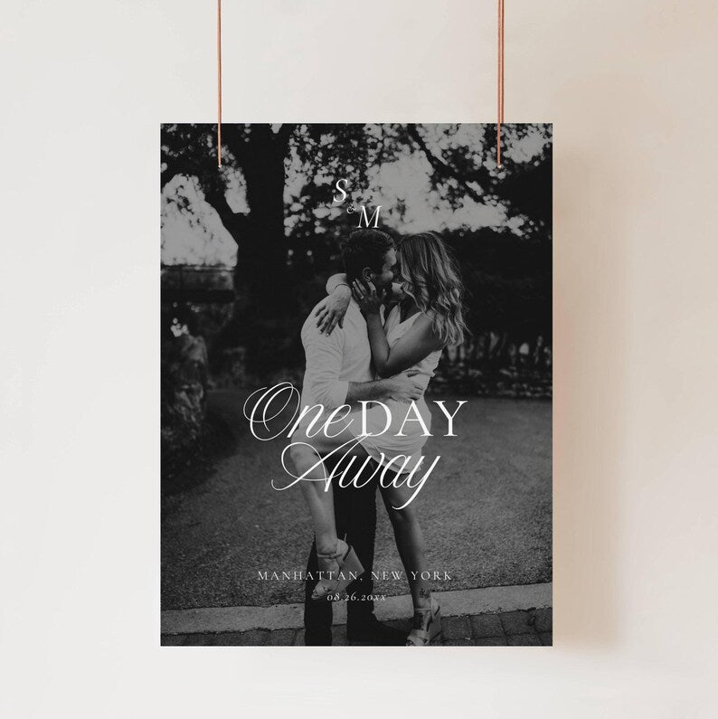 Black and white photo rehearsal welcome sign suspended by thin copper wires against a plain light wall