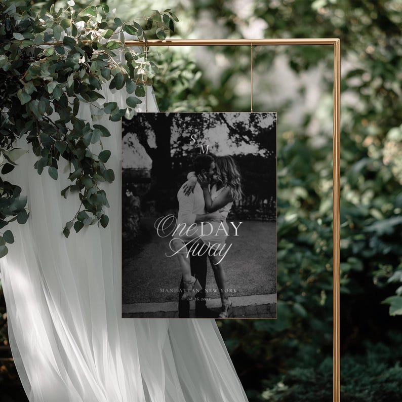 Black and white photo rehearsal welcome sign hanging from a gold metal frame decorated with eucalyptus branches