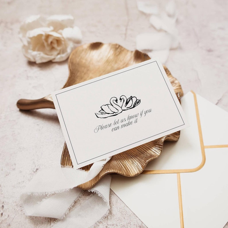 RSVP card with black swan illustration styled on gold tray with ribbon and envelope