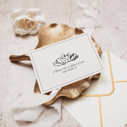 RSVP card with black swan illustration styled on gold tray with ribbon and envelope