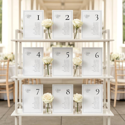 Seating chart cards displayed on a three-tiered stand with a single white rose