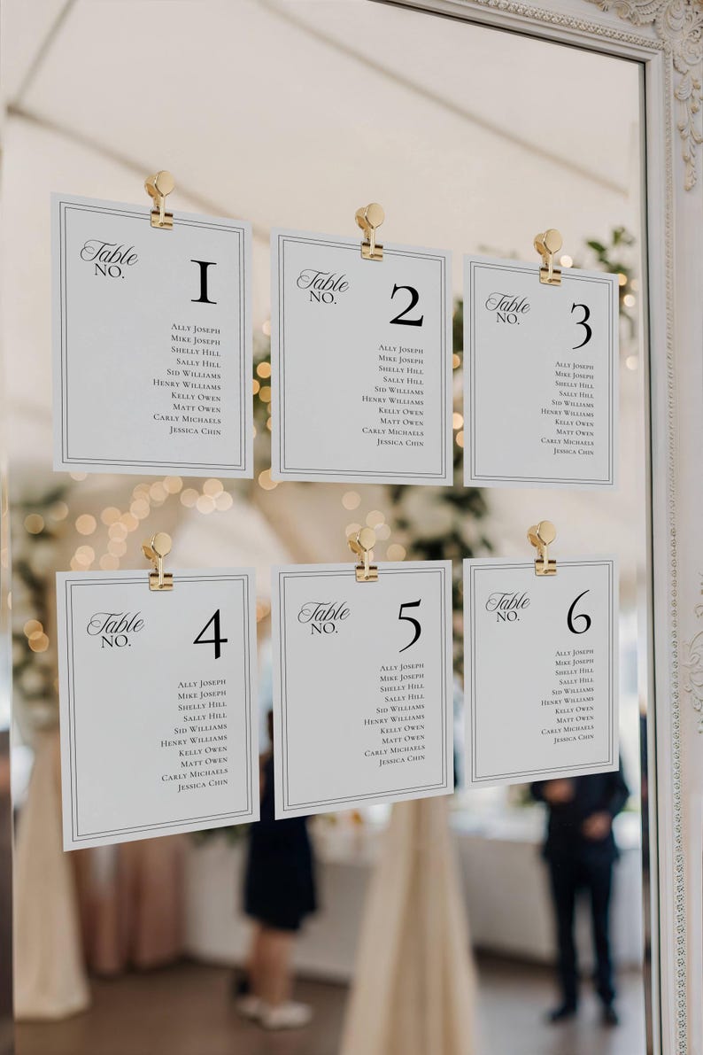 Seating chart cards clipped to an ornate mirror frame with gold clips