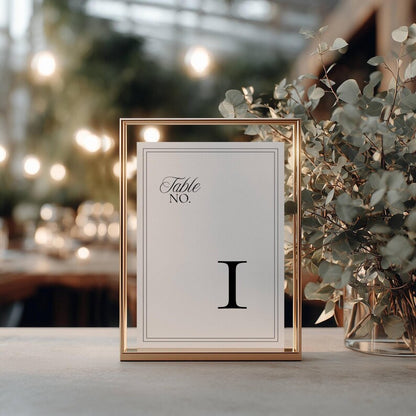 Minimalist wedding table number card with a black double-line border and Roman numeral I, displayed in a gold metal frame