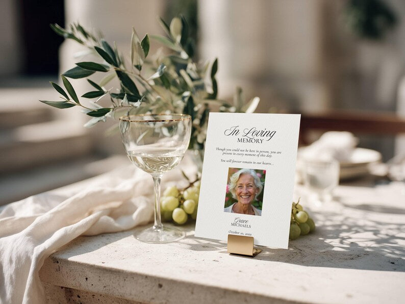 Photo in loving memory card held upright by a small gold stand on stone surface
