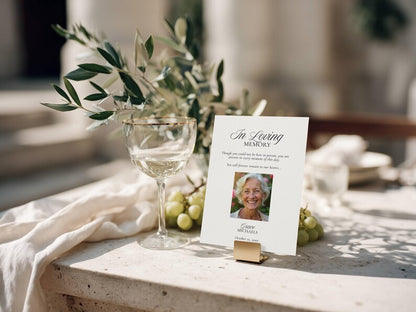Photo in loving memory card held upright by a small gold stand on stone surface