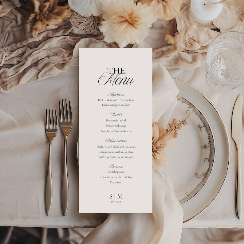 Vertical wedding menu card on off-white paper with black serif and script typography listing appetizers, starters, mains, and desserts, ending with initials S|M and date 10.10.XX
