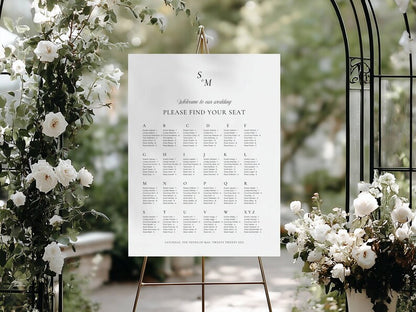 Alphabetical wedding seating chart on an easel surrounded by white and blush rose florals