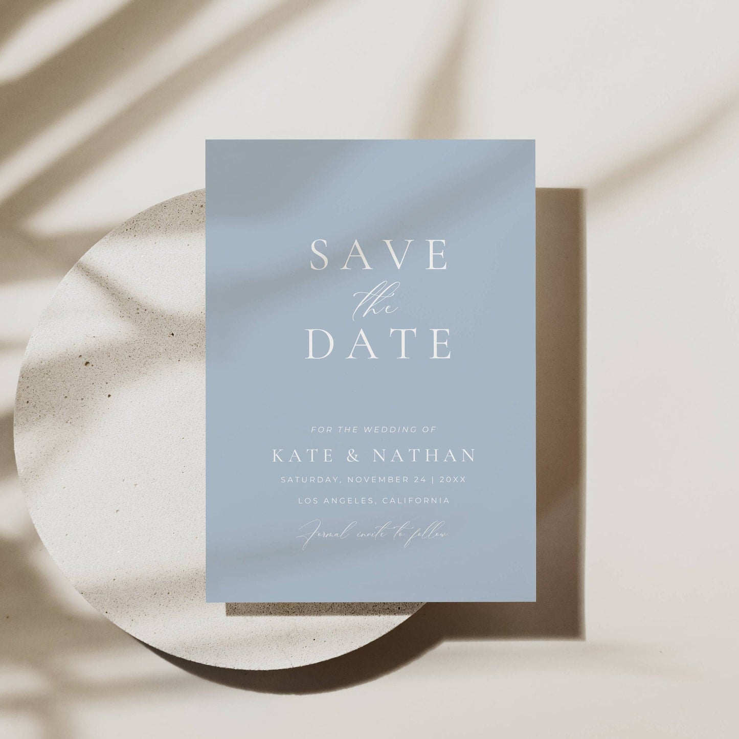 dusty blue save the date invitation on a plate with soft shadows