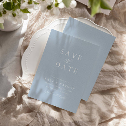 dusty blue save the date invitation on a plate with soft shadow