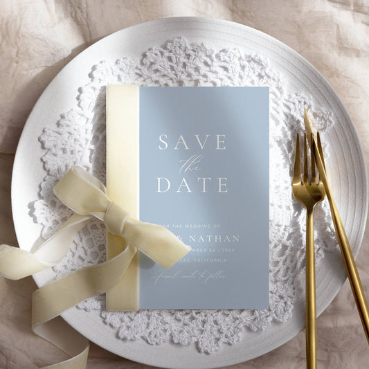 dusty blue save the date invitation on a plate with soft shadow