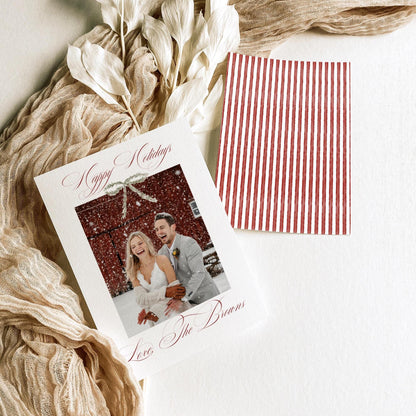 Double-sided 5x7 newlywed holiday card with red ribbon bow and striped back styled with dried white leaves