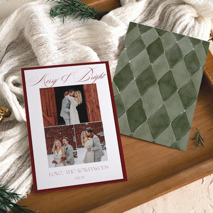 Burgundy Merry and Bright newlywed Christmas card with three wedding photos beside its sage green harlequin back, on a wooden tray